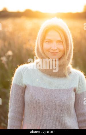 Portrait of Young Pretty Caucasian Happy Girl Woman in Woolen Jacket Bluse und Brown gestrickte Haube posiert im frühen Frühlingswald in Sunny Day. Viel Spaß Stockfoto