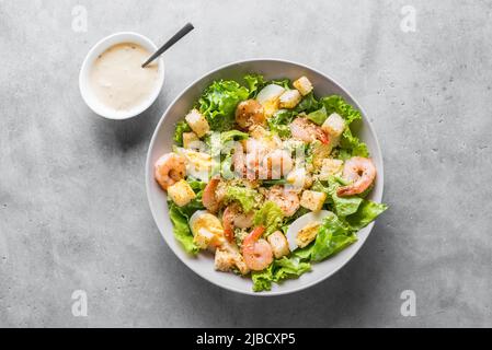 Garnelensalat. Meeresfrüchte Caesar Salat mit Garnelen, Parmesan-Käse und caesar-Dressing auf grauem Steingrund, Draufsicht, Kopierraum. Stockfoto
