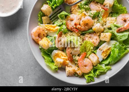 Garnelensalat. Meeresfrüchte Caesar Salat mit Garnelen, Parmesan-Käse und caesar-Dressing auf grauem Steingrund, Draufsicht, Kopierraum. Stockfoto