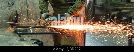 Schlosser arbeitet in der Produktion. Metallbearbeitung mit Winkelschleifer. Funken in der Metallbearbeitung. Stockfoto