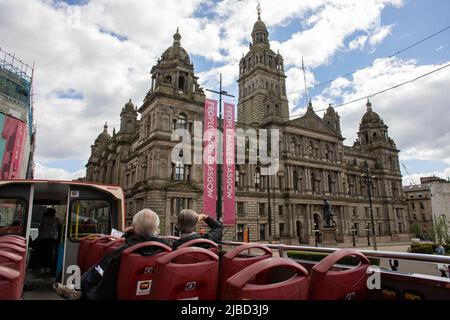 Menschen auf dem Oberdeck eines roten Touristenbusses, mit Blick auf das Stadtgebäude von Glasgow City Chambers am George Square, Glasgow, Schottland. Stockfoto