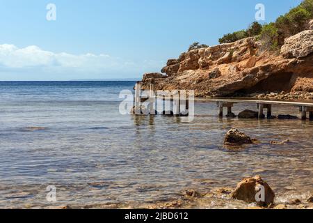 Winziger hölzerner Steg in Cala Bonita in einer flachen Bucht an der Südostküste von Ibiza, Balearen, Spanien Stockfoto