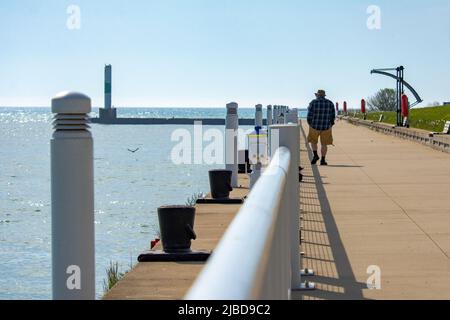 Ein Mann geht an einem kühlen Sommermorgen entlang des Zementweges im Coral Dock Park in Port Washington, Wisconsin. Stockfoto