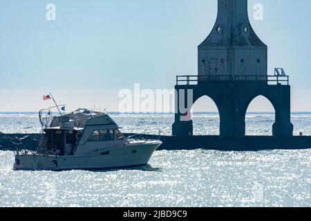 Ein nicht identifiziertes Boot fährt an einem Sommermorgen in der Nähe des Port Washington Break Water Light in Port Washington, Wisconsin, vorbei. Stockfoto