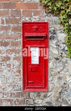 Traditioneller britischer roter Briefkasten in einer Wand aus viktorianischer Zeit, in Hampshire, England Stockfoto
