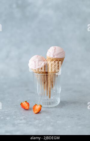 Cremiges veganes Erdbeereis im Horn in einem Glas auf grauem Hintergrund. Platz für Text. Gesundes veganes Dessert Stockfoto