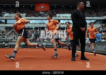 Paris, Frankreich. 05.. Juni 2022. Ballkinder kommen während einer Pause beim Finale der French Tennis Open zwischen Rafael Nadal aus Spanien und Casper Ruud aus Norwegen am Sonntag in Roland Garros, außerhalb von Paris, Frankreich, an einem Sicherheitsbeamten vorbei, der auf dem zentralen Platz steht. 5. Juni 2022. Die Sicherheit wurde um das Gericht herum verstärkt, nachdem eine Klimaaktivistin, die sich an das Netz gebunden hatte und am Freitag, dem 3. Juni, ein Halbfinalspiel unterbrach. Foto von Maya Vidon-White/UPI Credit: UPI/Alamy Live News Stockfoto