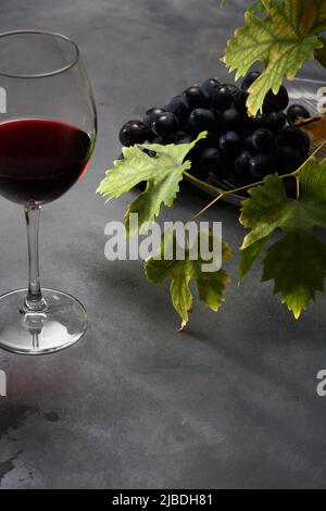 Rotwein und Trauben. Wein und Trauben im Vintage-Ambiente auf dem Tisch. Dunkler Hintergrund. Stockfoto