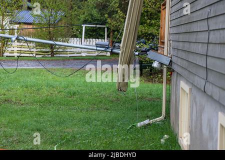 Blick von der Seite eines freistehenden Hauses mit Rinne abgerissen und abgetrennte Versorgungskabel nach starken Winden und stürmischem Wetter. Mit Kopierbereich. Stockfoto