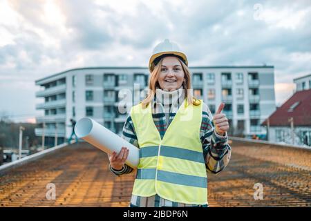 Kaukasische 30s Ingenieurin Frau trägt Uniform und Sicherheitshelm unter Inspektion und Überprüfung der Konstruktion Stockfoto