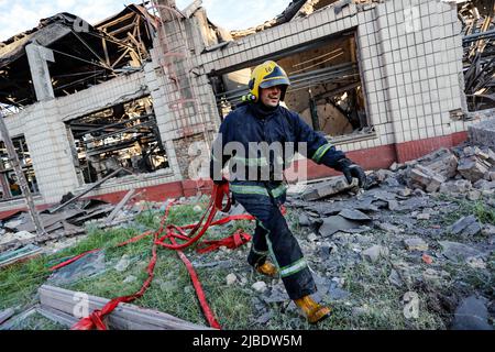 Kiew, Kiew, Ukraine. 5.. Juni 2022. Nach einer Reihe von russischen Luftangriffen auf das Gebiet, bei denen mindestens ein Mann verletzt wurde, haben die Feuerwehrleute das Feuer auf ein beschädigtes Gebäude in einer Eisenbahnreparaturanlage in Kiew gelöscht, da Russland behauptete, dass in dem Gelände osteuropäische Militärwaffen und -Fahrzeuge gelagert wurden. Die Hauptstadt hat seit Wochen keine russischen Angriffe mehr erlebt, bevor dieser Luftangriff die Reparaturanlage traf, wobei Moskau die Offensive auf den Donbass intensiviert. (Bild: © Daniel Ceng Shou-Yi/ZUMA Press Wire) Stockfoto