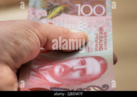 Weibliche Hand mit einer neuseeländischen 100-Dollar-Banknote Stockfoto