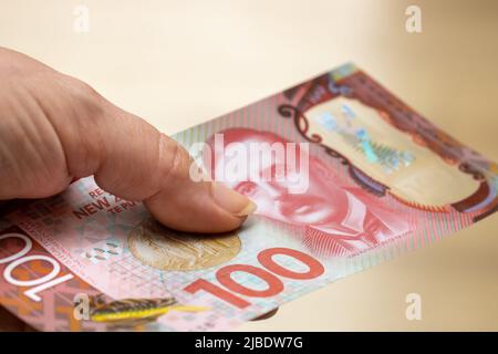 Weibliche Hand mit einer neuseeländischen 100-Dollar-Banknote Stockfoto