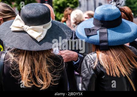 Epsom Surrey, London, Großbritannien, 04 2022. Juni, zwei Frauen tragen große, blau umrandte Hüte Zurück zur Kamera langes braunes Haar Stockfoto