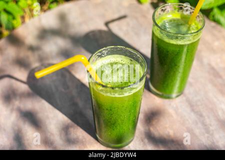 Getränke aus frischem Gemüse, Smoothies aus grünen, mit Chlorophyll gesättigten Blättern auf einem Tisch im Garten. Gesunde Ernährung. Stockfoto