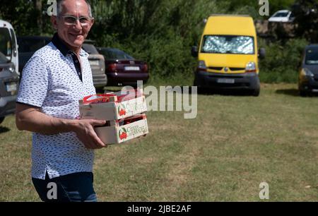 Terrades, Spanien. 05.. Juni 2022. Ein Mann wird gesehen, wie er den Parkplatz mit einer Kiste Kirschen betrat. Nachdem die XXV Fira Mercat de la cirera (Kirschenmesse) wegen Covid-19 für zwei Jahre in Folge ausgesetzt wurde, fand sie wieder in Terrades, Girona, statt. Kredit: SOPA Images Limited/Alamy Live Nachrichten Stockfoto