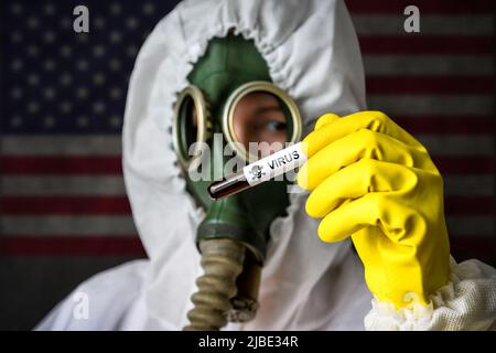 Geheimlabor, Wissenschaftler in Schutzanzug und Gasmaske hält Reagenzglas mit gefährlichen Virus auf USA Flagge Hintergrund. Konzept der giftigen Chemikalien und Biolo Stockfoto