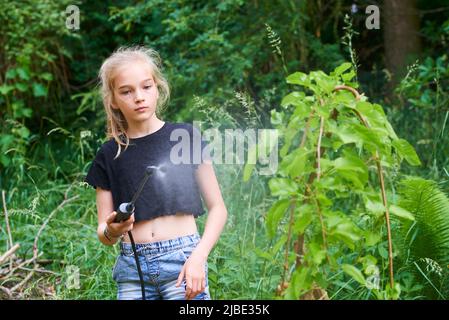 Teenager-Mädchen sprühen ökologische Produkt gegen Blattläuse und andere Schädlinge auf Obstbäume und andere Bäume im Garten und Obstgarten. Selektiver Fokus Stockfoto