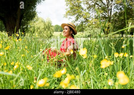 Porträt der schönen asiatischen Frau saß auf einem Feld genießen die Sonne Stockfoto