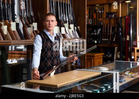 Der Besitzer des Waffenladens zeigt ein seltenes Sammlergewehr Stockfoto