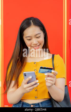 asiatische Frau, die eine Zahlung mit ihrem Smartphone macht Stockfoto