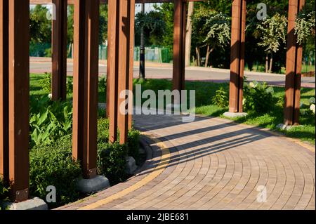 Gepflasterte Steinwege mit farbigen roten und gelben Ziegeln mit Fahrradmarkierungen im Grünen, städtische Landschaftsgestaltung mit Pflanzen im Landschaftsdesign, Park auf Stockfoto