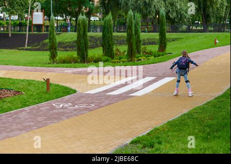 Gepflasterte Steinwege mit farbigen roten und gelben Ziegeln mit Fahrradmarkierungen im Grünen, städtische Landschaftsgestaltung mit Pflanzen im Landschaftsdesign, Park auf Stockfoto