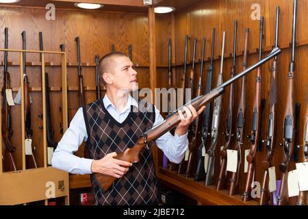 Porträt des Kunden, der Kampf Gewehrgewehr in Armee-Markt zu wählen. Stockfoto