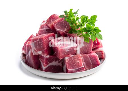 Frisches rohes Schweinefleisch in Keramikplatte auf weiß isoliert Stockfoto