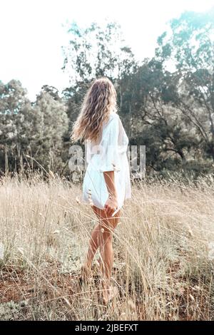 Spirituelles Mädchen in weißem Kleid, das im Wald auf dem Feld steht. Stockfoto