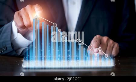 Geschäftsmann Hand mit Tablet mit kreativen glühenden Pfeil und Stock Chart. Hand des Geschäftsmannes verwenden Tablettenanalyse Aktienmarkt Grafik Wachstum und Ankurbelung Stockfoto