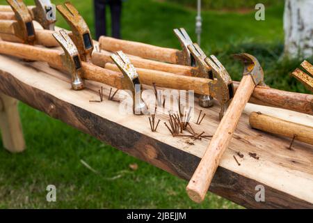 Ein unordentlicher Haufen rostiger Nägel und Hämmer auf einem Holzbrett Stockfoto