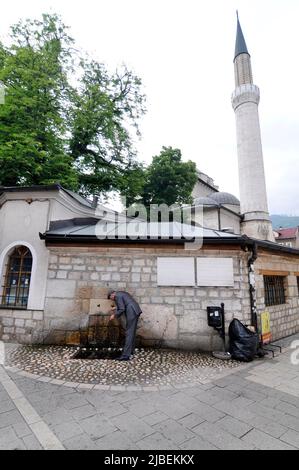 Ein bosnischer Mann trinkt Wasser aus dem Trinkbrunnen der Gazi-Husrev-Beg-Moschee Stockfoto