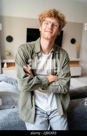 Junger irischer Ingwer in einer Brille, der die Hände auf dem Brustportrait kreuzt Stockfoto