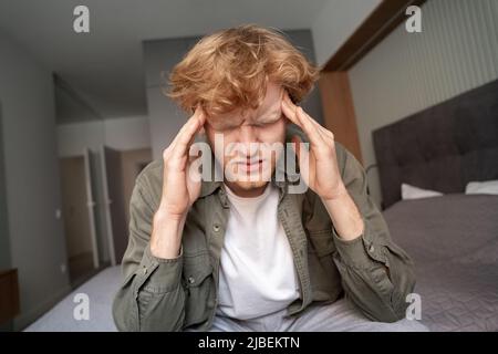 Junger Ingwer, der unter schrecklichen Kopfschmerzen oder Migräne leidet, wurde in Nahaufnahme aufgenommen Stockfoto