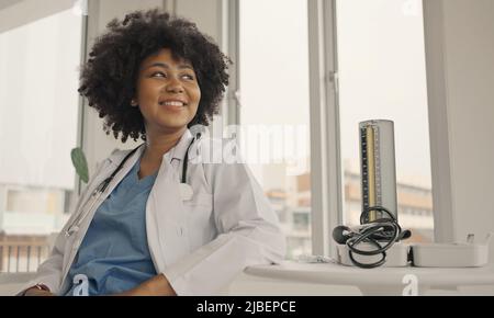 Porträt einer lächelnden Ärztin in einem Krankenhausbüro, die einen weißen Mantel mit Stethoskop trägt. Stockfoto