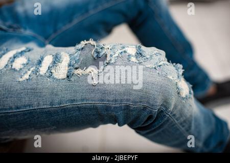 Der Mann trägt eine bekümmerte Jeans. Jeans in Blau. Nahaufnahme bei zerrissenen Jeans. Stockfoto