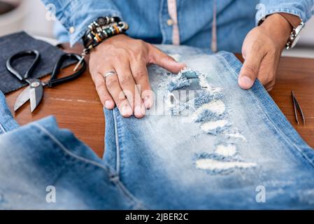 Schneiderarbeit mit Jeans aus blauem Denim. jeanshose reparieren. Stockfoto