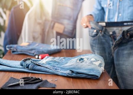 Schneiderarbeit mit Jeans aus blauem Denim. jeanshose reparieren. Stockfoto