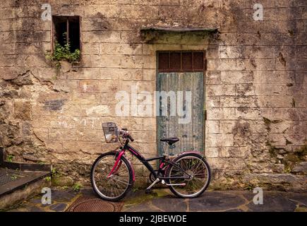 Fahrrad vor der verwitterten Tür in Cinque Terre, die aus fünf schönen Küstendörfern besteht, die durch Wanderwege am Klippenrand verbunden sind Stockfoto