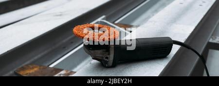 Sander für Metallträger auf der Baustelle. Professionelle tragbare moderne kleine Schleifmaschine auf Aluminium-Säule, niemand. Rotorblatt der Windenergieanlage Stockfoto