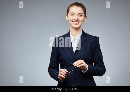 Porträt einer jungen Geschäftsfrau, die lächelt und die Brille in der Hand hält und den Raum kopiert Stockfoto