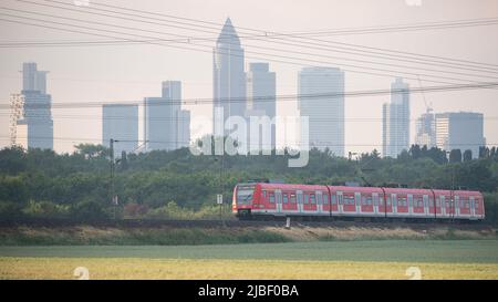 06. Juni 2022, Hessen, Frankfurt/Main: Die S-Bahn zwischen Friedrichsdorf und Frankfurt am Main Südbahnhof (S5) verläuft vor der Kulisse der Frankfurter Skyline. Dank des 9-Euro-Tickets waren am Pfingstwochenende mehr Fahrgäste in den Zügen in Hessen unterwegs. Foto: Sebastian Gollnow/dpa Stockfoto