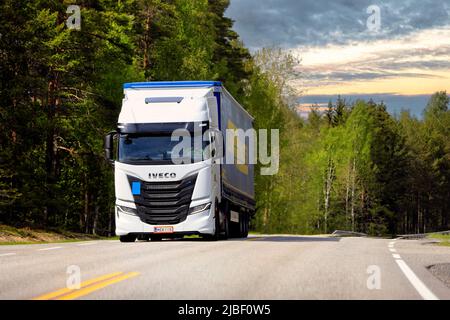 Weißer gasbetriebener Iveco S-Way Natural Power, NP, LKW vor Sattelauflieger auf Highway 52 im goldenen Stundenlicht. Raasepori, Finnland. 26.Mai 2022. Stockfoto