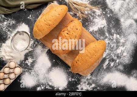 Drei Brote aus Weizen, Mais und Roggenmehl. Vielfalt an Backwaren auf Holzhintergrund. Mini-Bäckereikonzept. Stockfoto