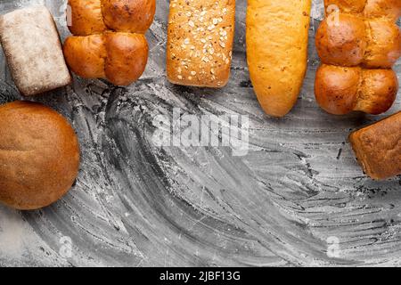 Frisch gebackenes Brot auf schwarzer Tischplatte, Backwaren und gesunde Lebensmittel flach legen Stockfoto