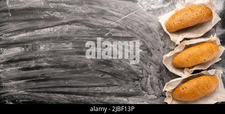 Auswahl an leckeren frisch gebackenen Broten auf schwarzem Beton-Hintergrund mit Mehl Draufsicht Copy Space, Banner Stockfoto