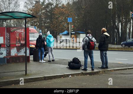 Öffentliche Verkehrsmittel Menschen mit Rucksack schauen auf ankommende Straßenbahn an der Haltestelle des öffentlichen Verkehrs in der Stadt Rückansicht Stockfoto