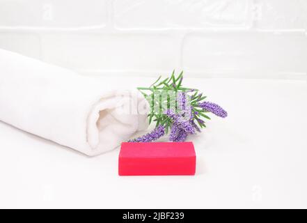 Flauschiges Handtuch, rosa Seife, Lavendel auf weißem Hintergrund im Bad. Konzept der Hygiene. Speicherplatz kopieren Stockfoto