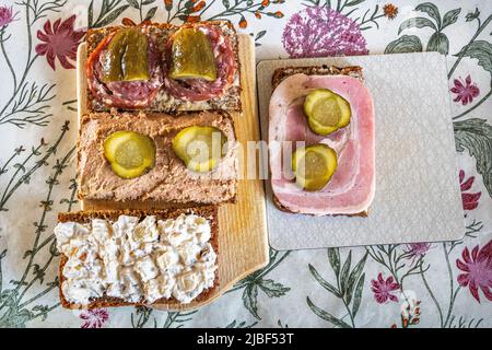 Typische Zutaten einer dänischen hausgemachten smørrebrød. Rullepølse auf Schwarzbrot, Gurke, Leberpastete und Zwiebelsalami. Assens, Dänemark, Europa Stockfoto